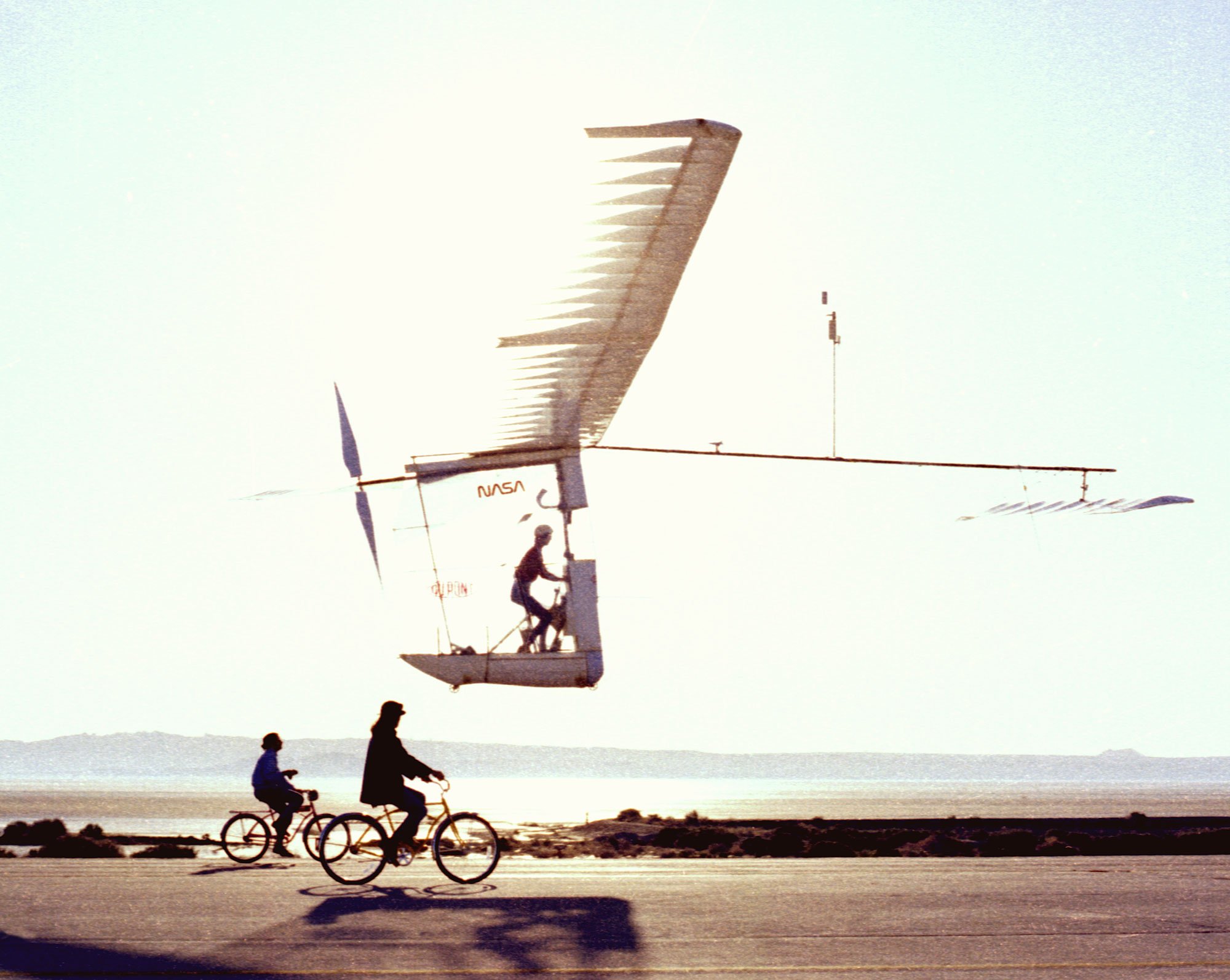 Gossamer Albatross in flight, with two bicycles following it on the ground